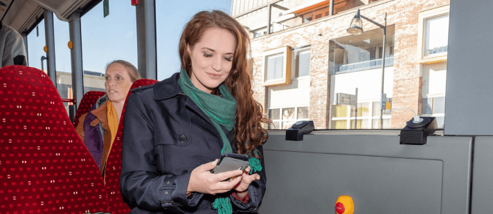 Vrouwelijke reiziger in de bus op haar telefoon