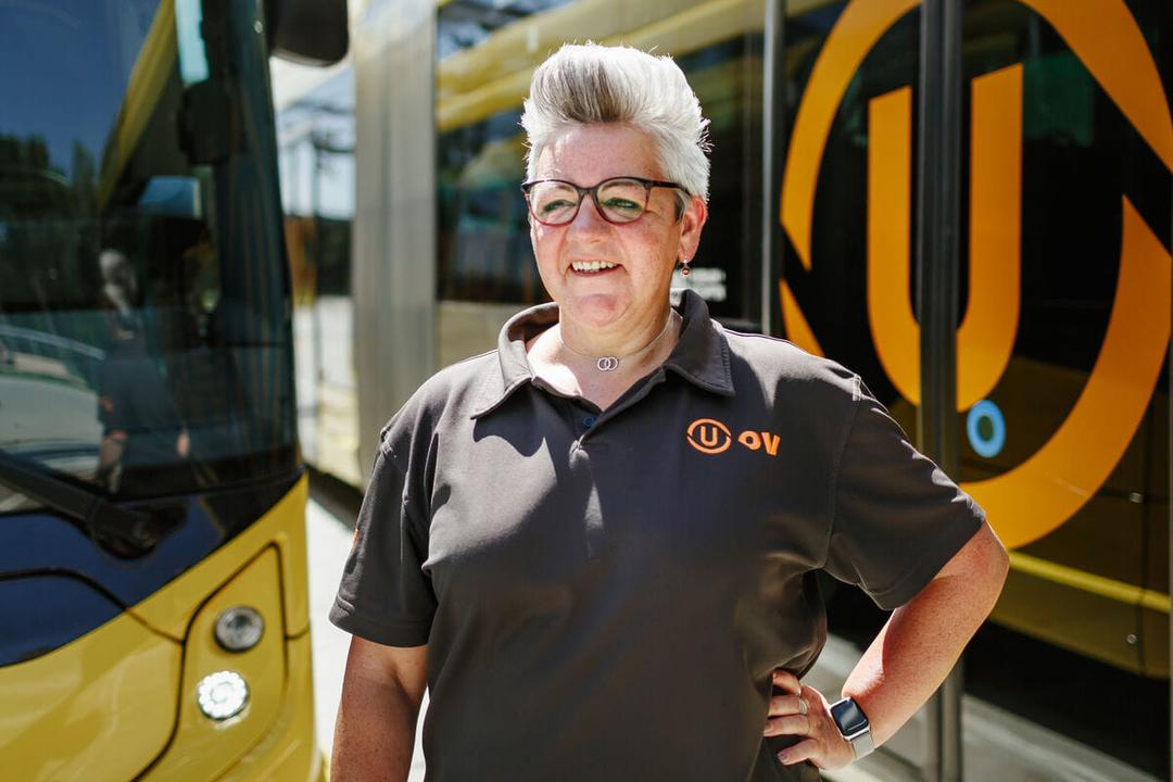 Buschauffeuse van U-OV staat op lachend op de foto voor een bus