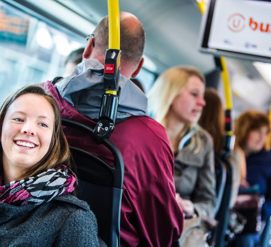 Reizigers zitten in een bus met advertentiescherm op achtergrond